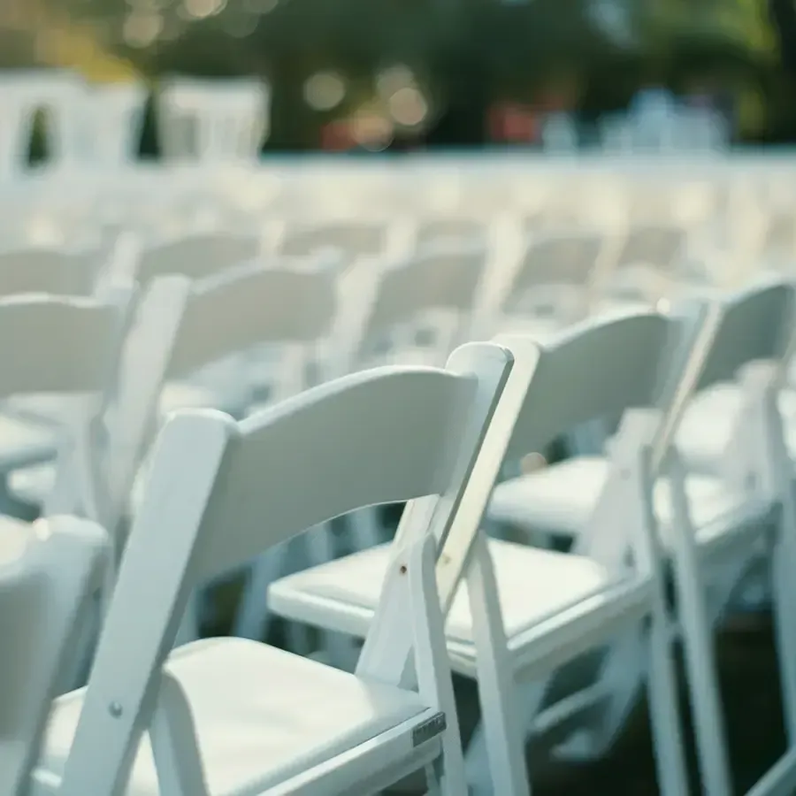 Rows of white folding chairs arranged outdoors at a blurred event venue