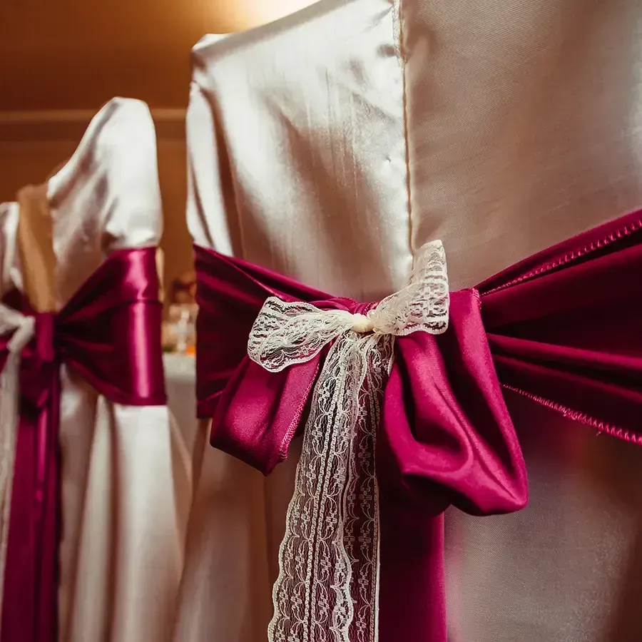 Cream dresses with magenta satin waist sashes and lace bows on mannequins