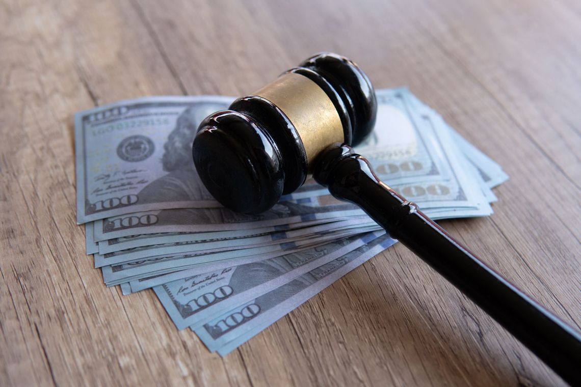Judge’s gavel on a stack of dollar bills on a wooden table