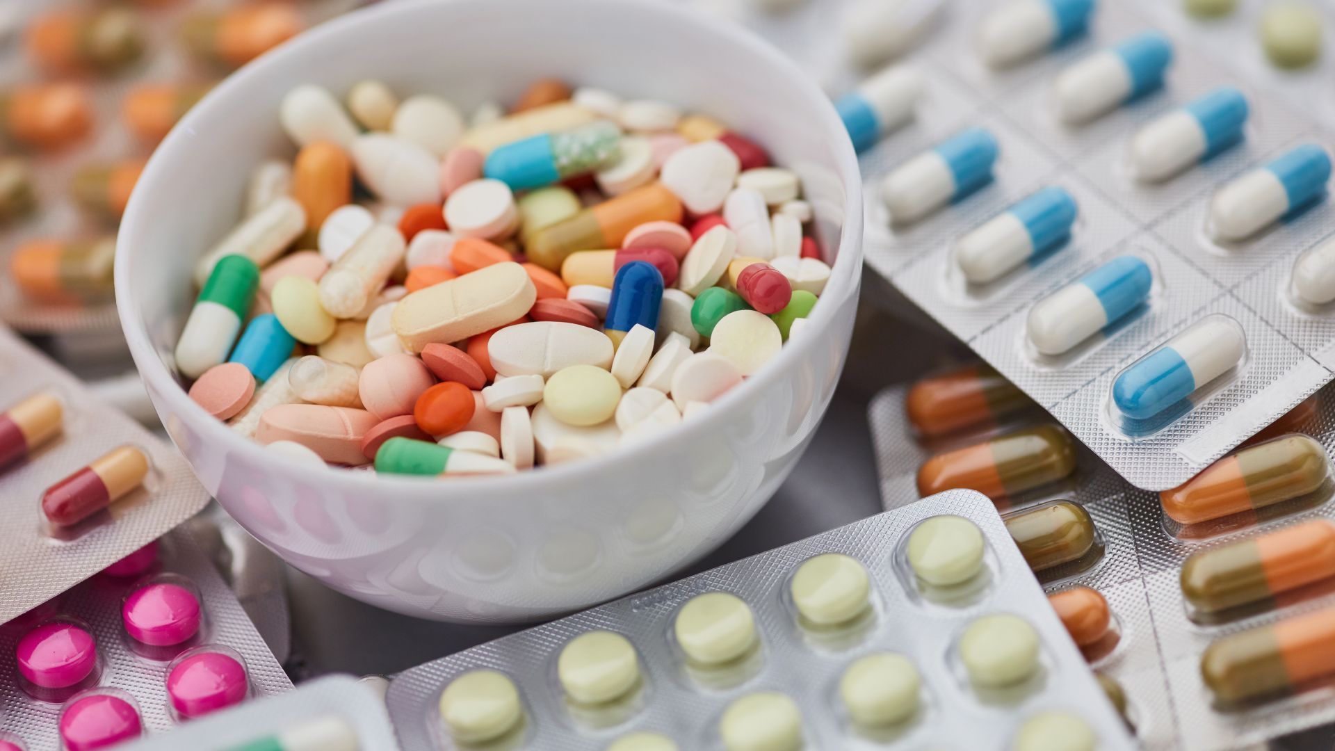 There are many different types of pills in a bowl.
