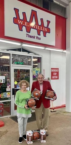 A man and a woman are holding basketballs in front of a store.