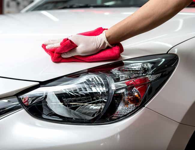 technician wiping down the hood of a car