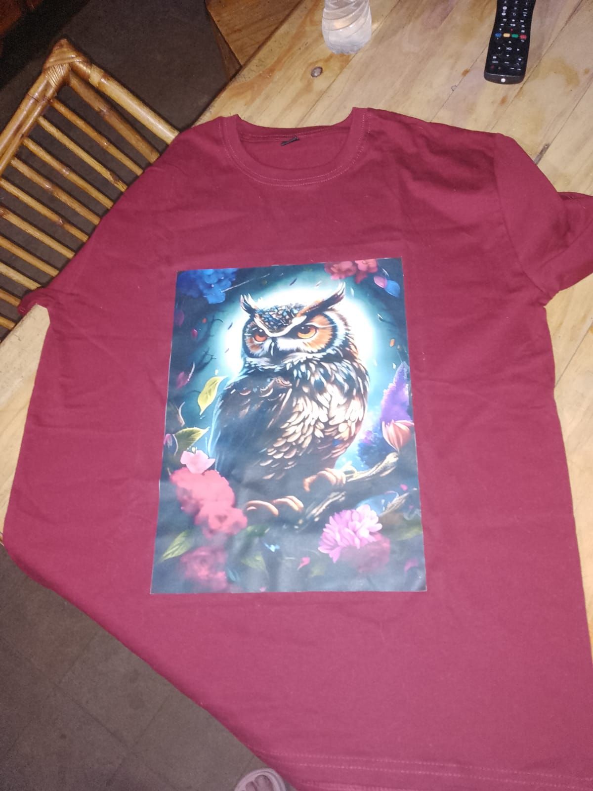 Camiseta burdeos con un colorido diseño de búho en la parte delantera. El búho está posado en una rama, rodeado de flores.