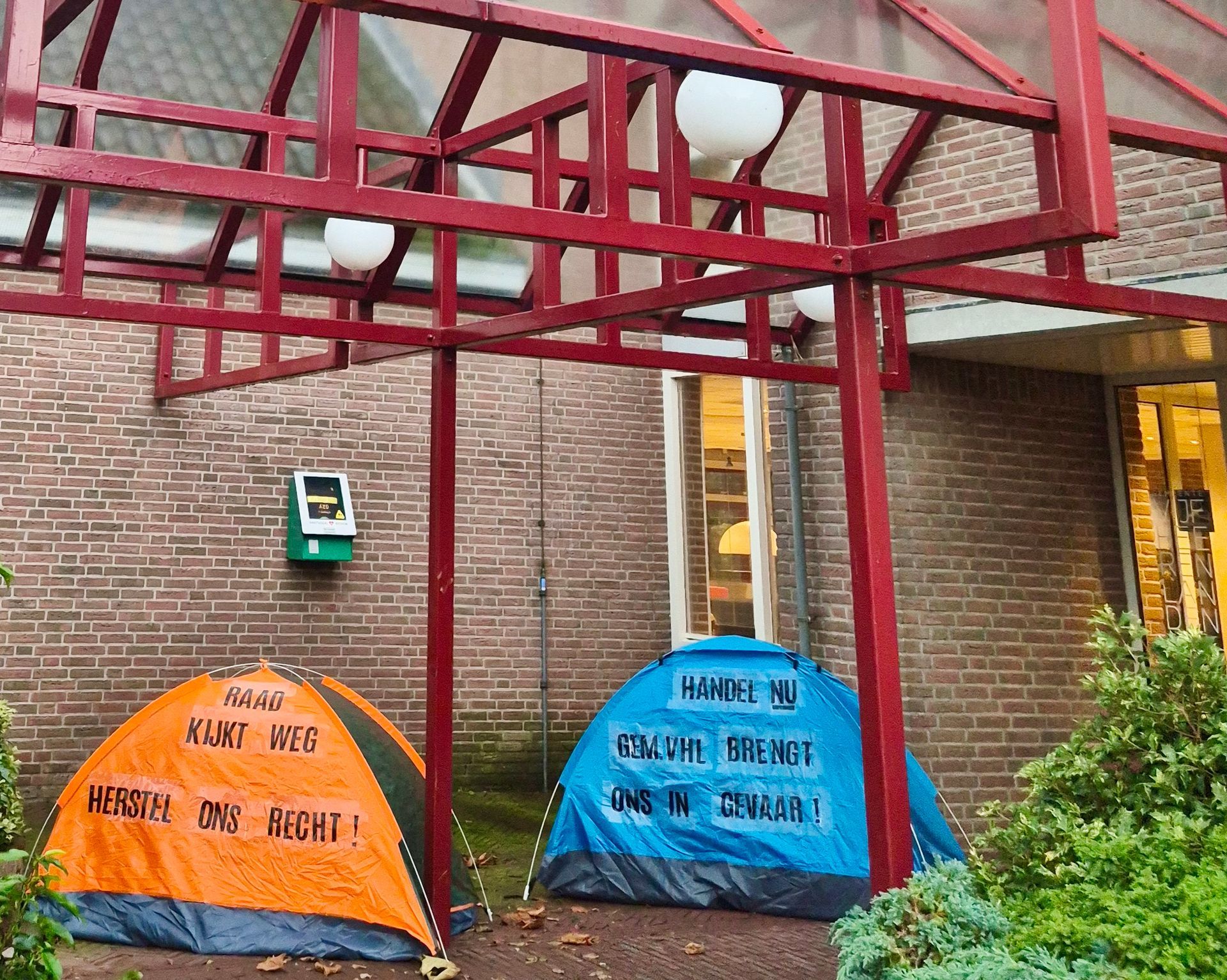 Twee tenten staan voor een bakstenen gebouw.