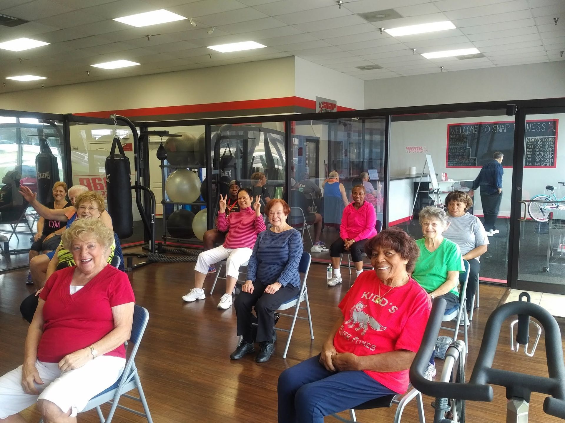 People seated in a gym studio, facing forward during a fitness class