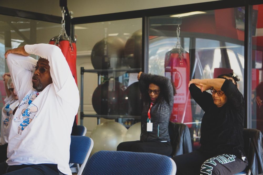 People stretching in a gym with punching bags in the background