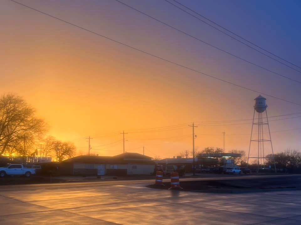 A sunset over a parking lot with a water tower in the background.