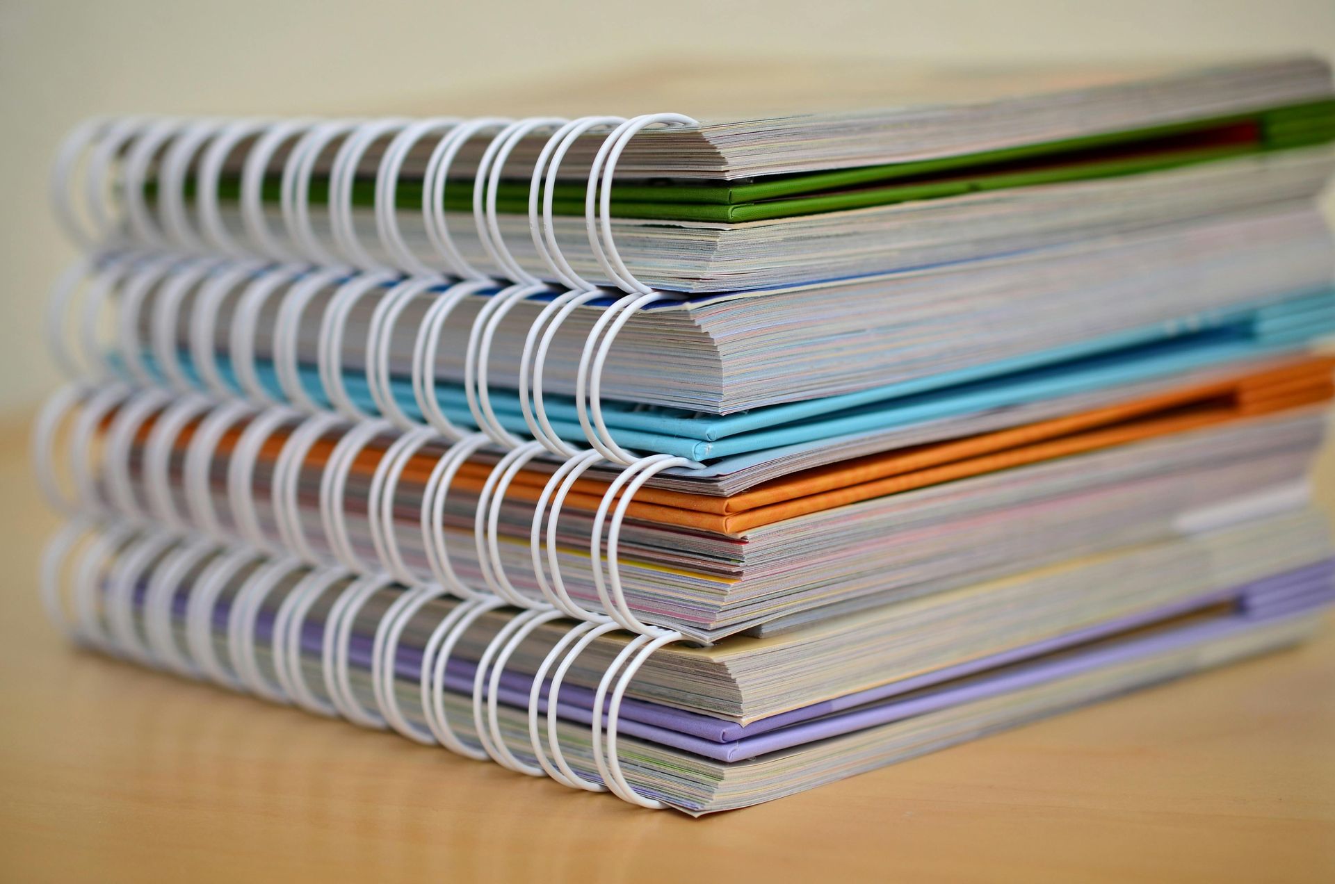 A stack of spiral notebooks sitting on top of each other on a table.