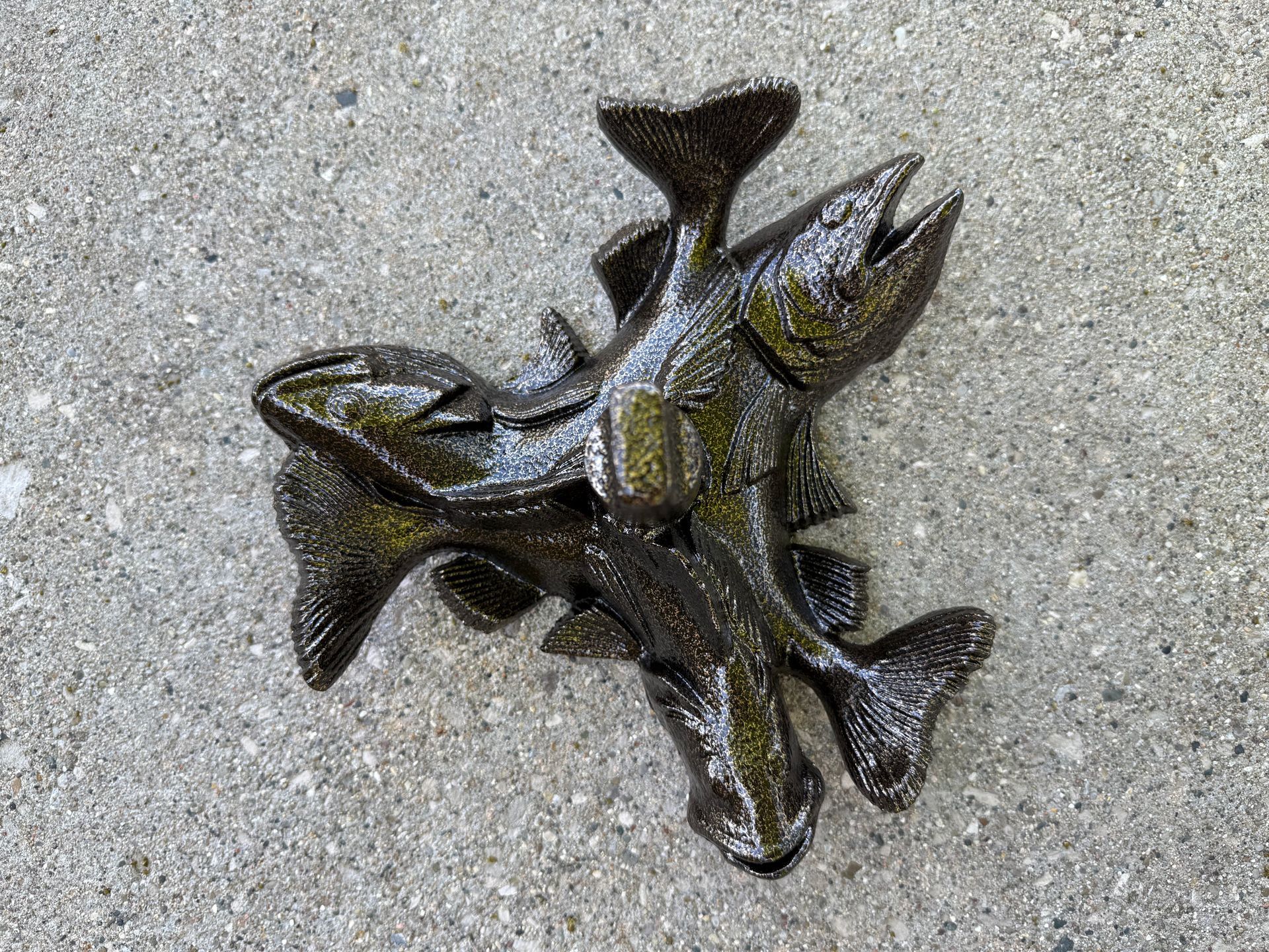 Cluster of dark fish-shaped metal sculptures on gray pavement