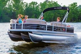 A group of people are riding a pontoon boat on a lake.