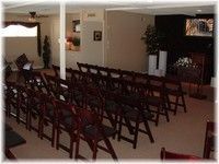 Rows of wooden chairs arranged in a room with a fireplace and warm lighting