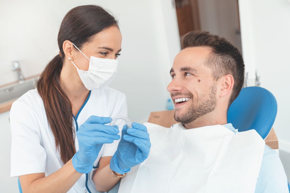 A Man Is Sitting In A Dental Chair While A Female Dentist Examines His Teeth — Cairns Precision Dental Group In Woree, QLD
