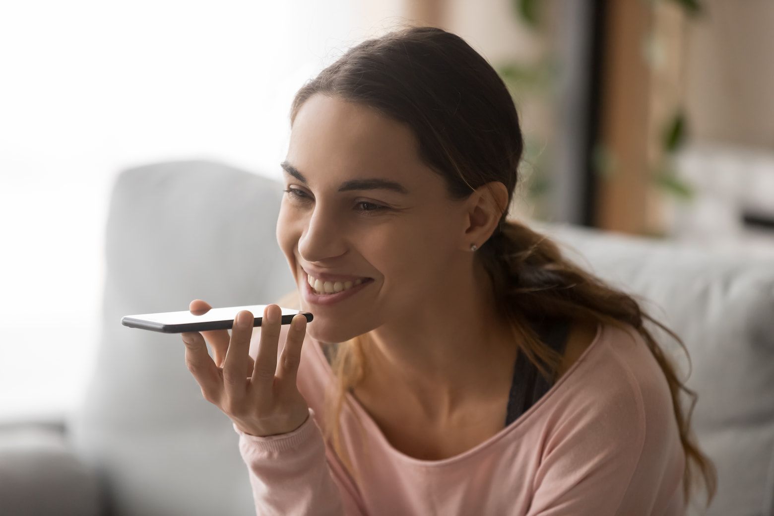 A Woman Is Sitting On A Couch Talking On A Cell Phone — Cairns Precision Dental Group In Woree, QLD
