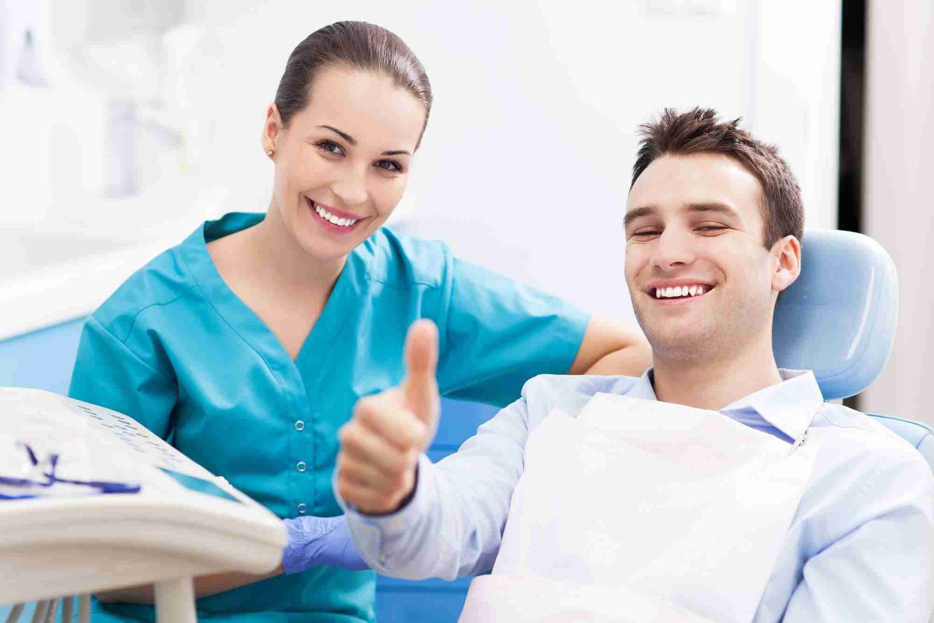 A Dentist is Giving a Thumbs Up to a Patient in a Dental Chair — Cairns Precision Dental Group In Woree, QLD