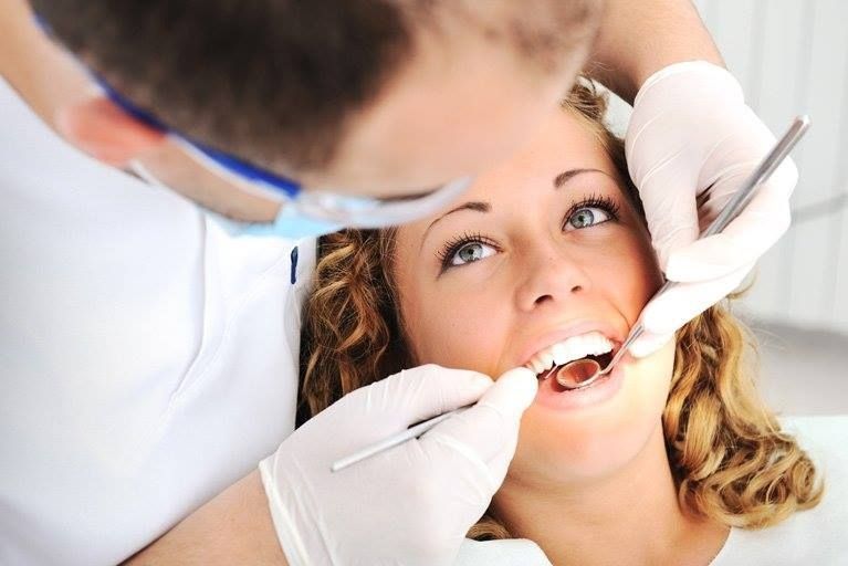 A Man is Talking to a Woman Who is Getting an X-ray of Her Teeth — Cairns Precision Dental Group In Woree, QLD