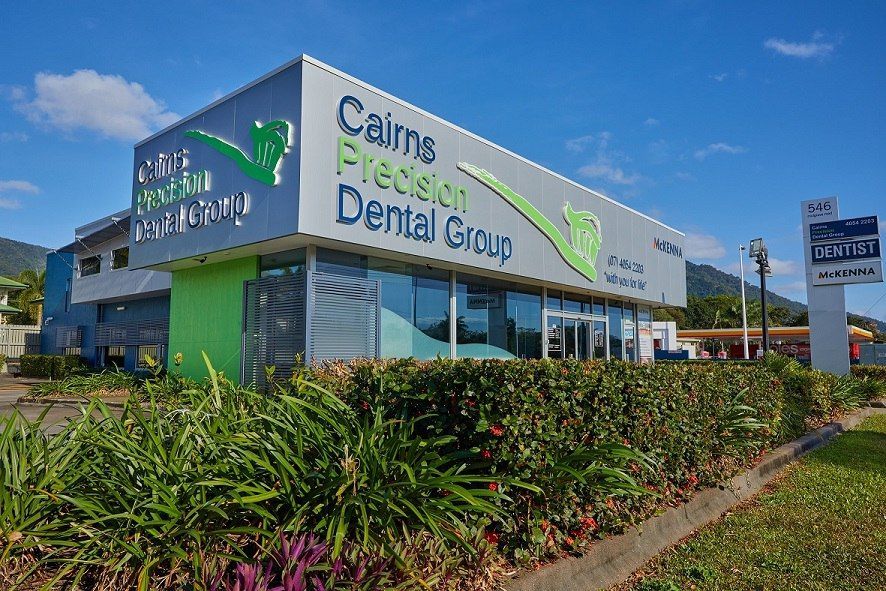 A Man is Standing in a Kitchen Holding a Wrapped Gift — Cairns Precision Dental Group In Woree, QLD
