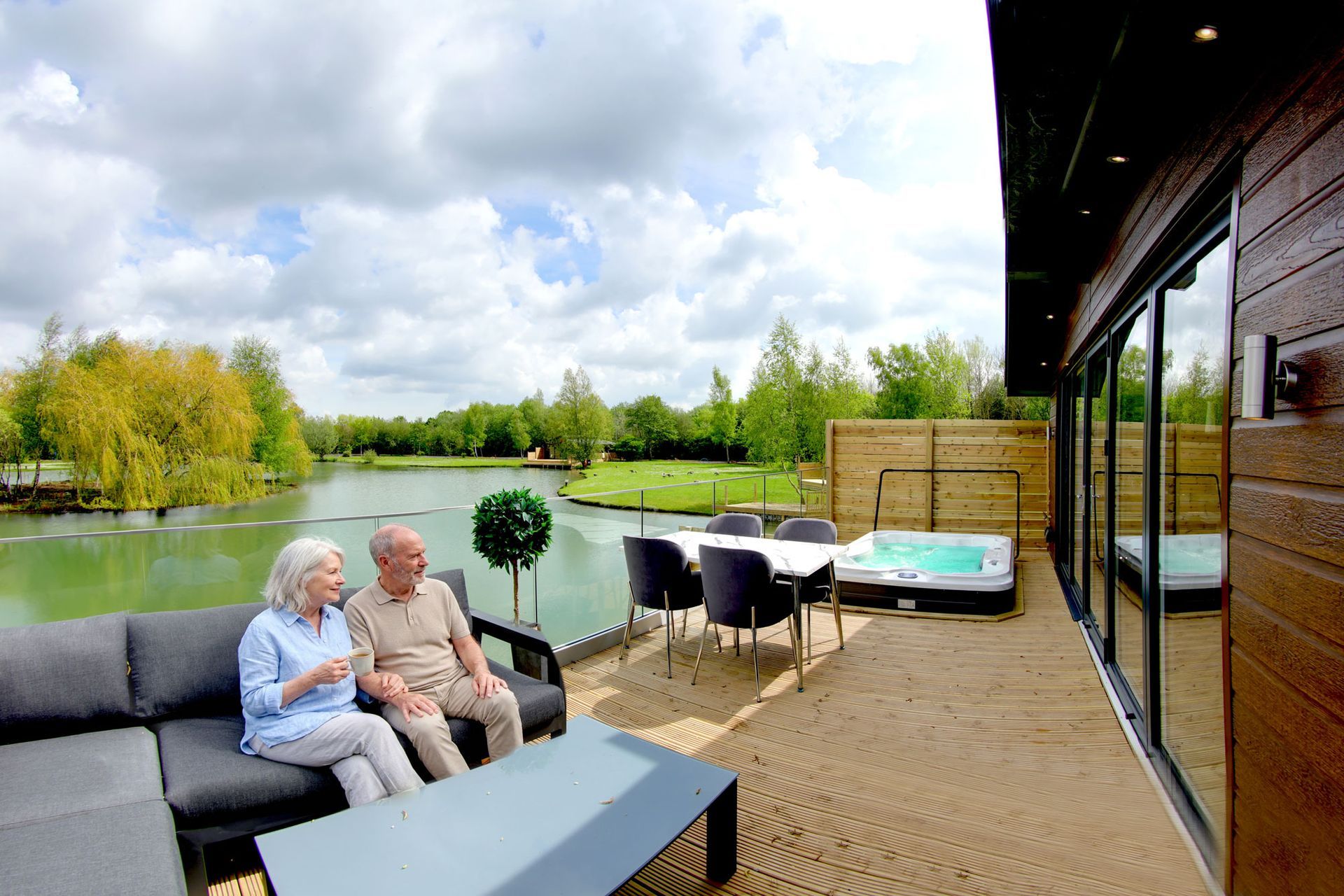 Retired couple laughing on a lakeside decked terrace in warm evening light