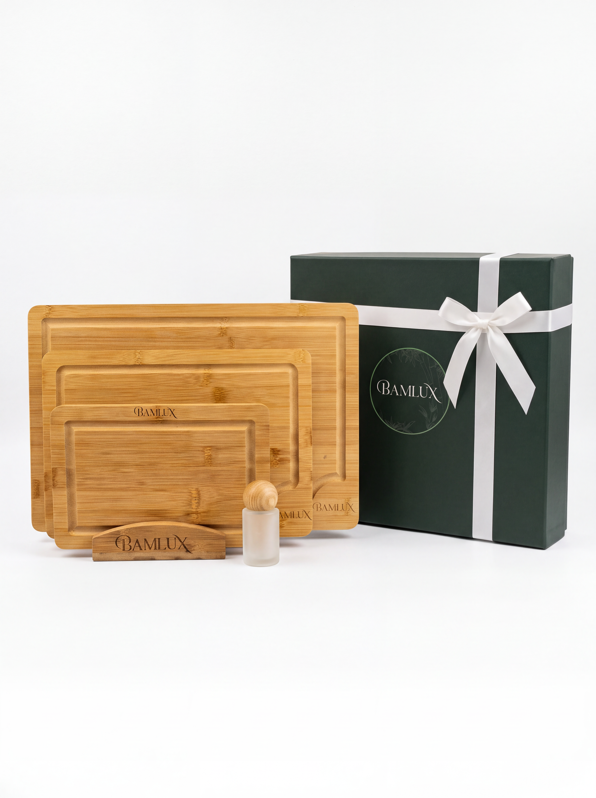 Set houten snijplanken met een donkergroene geschenkdoos, gestrikt met een wit lint, op een witte achtergrond