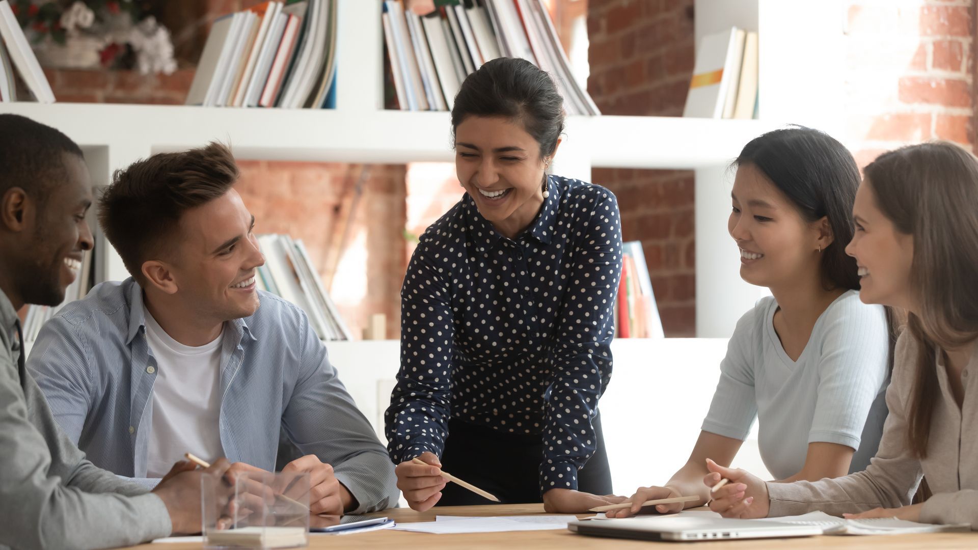 A group of people are sitting around a table having a meeting.