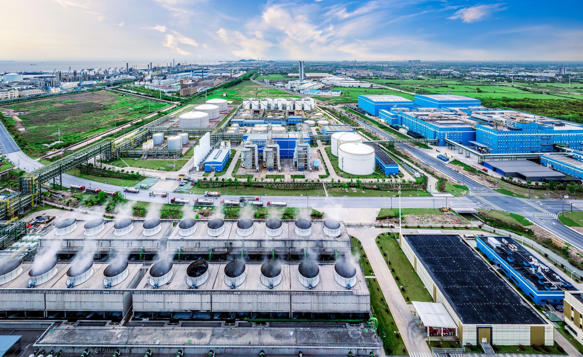 Aerial view of an industrial water treatment plant with tanks, buildings, and green surroundings near a coastline.