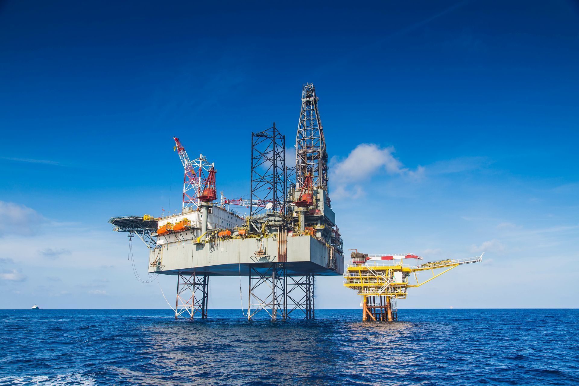 Offshore oil rig in a blue ocean, under a bright blue sky.