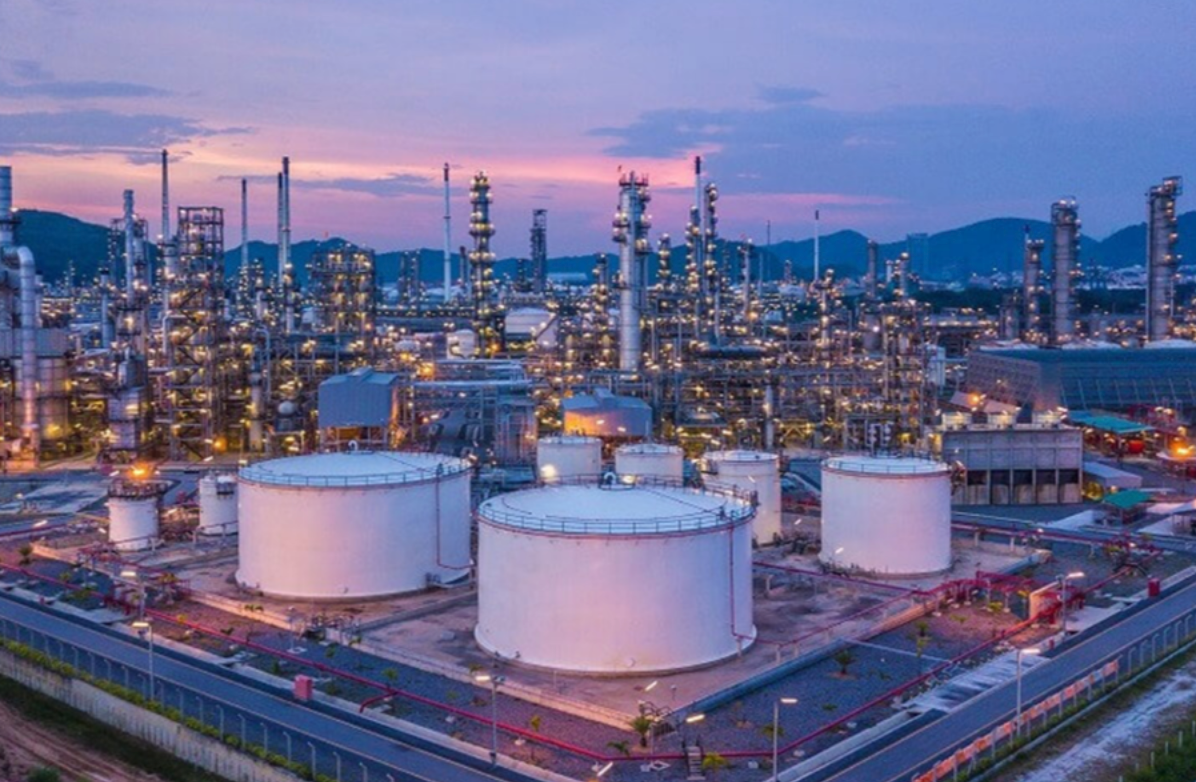 Oil refinery with storage tanks, pipes, and towers at dusk.