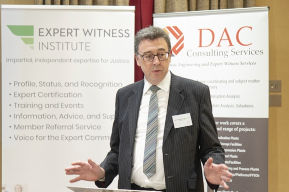 Man speaking at a podium with banners for 