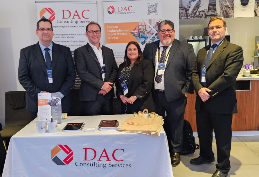 Five people at a booth for DAC Consulting Services; banner shows logo.