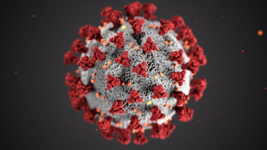 Coronavirus, gray sphere with red spiky protrusions, against a dark background.