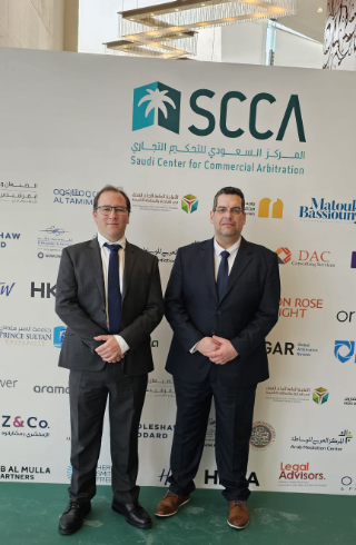 Two men in suits stand in front of a SCCA banner with logos.