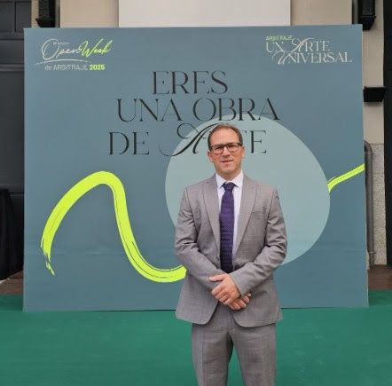Man in a suit stands in front of a backdrop that reads 
