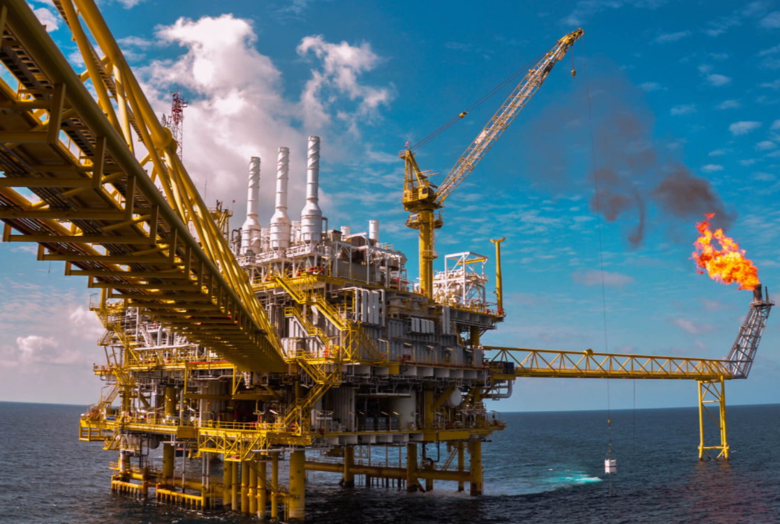 Offshore oil platform in ocean, yellow structure with flame burning.