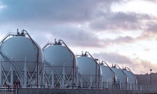 Large white spherical storage tanks at an industrial facility against a cloudy sky.