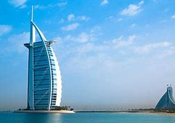 Burj Al Arab hotel in Dubai, a sail-shaped luxury building by the sea against a clear blue sky.