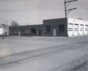 A black and white photo of a brick building with white garage doors.