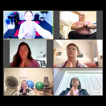 Six people in a video call, practicing yoga with hands in prayer position.