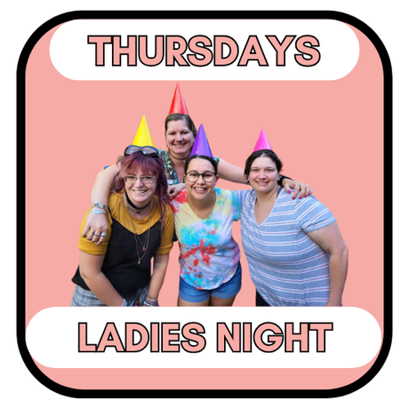 Four women in party hats, hugging, celebrating 