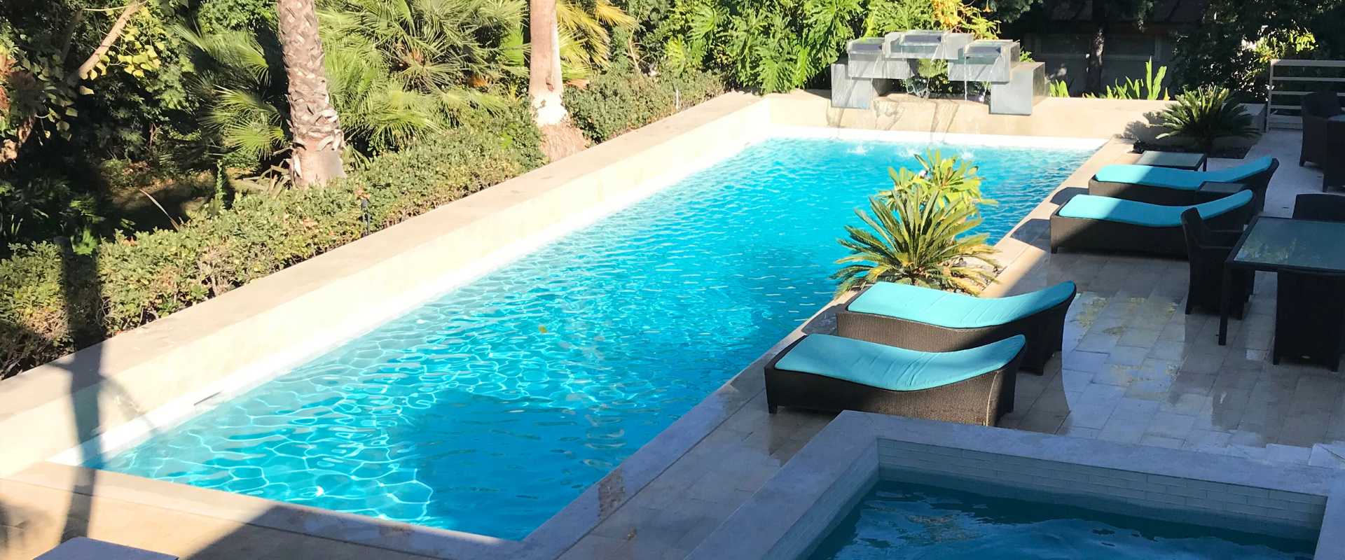 Swimming pool with white deck and furniture in an outdoor setting.