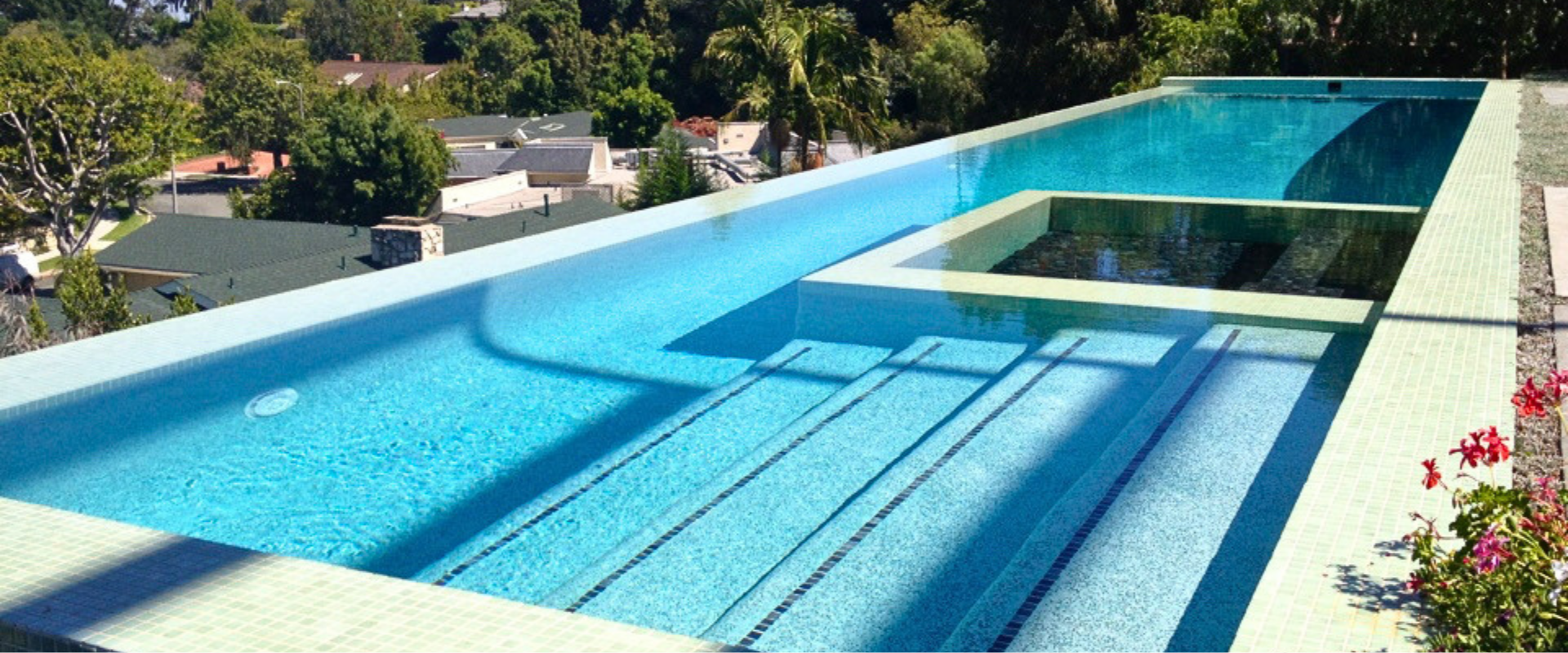 Swimming pool with white deck and furniture in an outdoor setting.