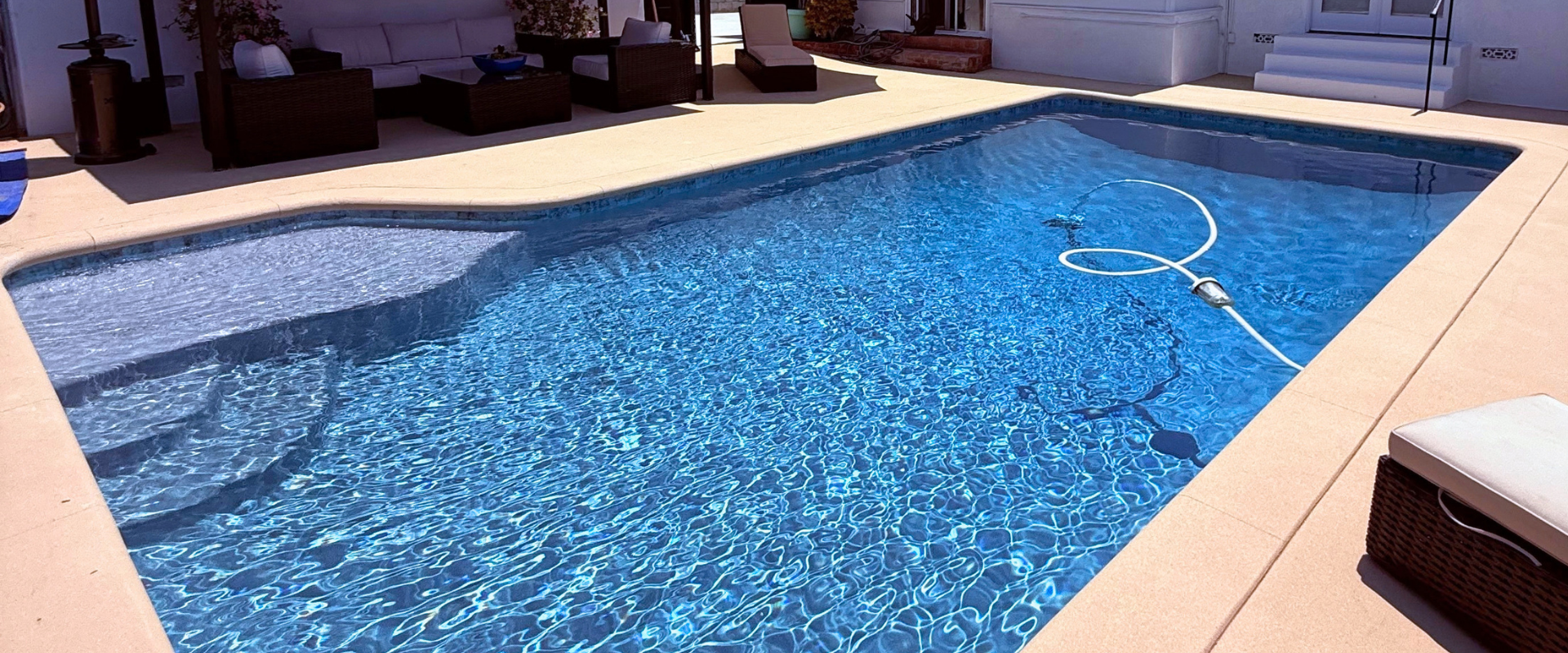 Backyard swimming pool with clear blue water and a pool skimmer floating on the surface