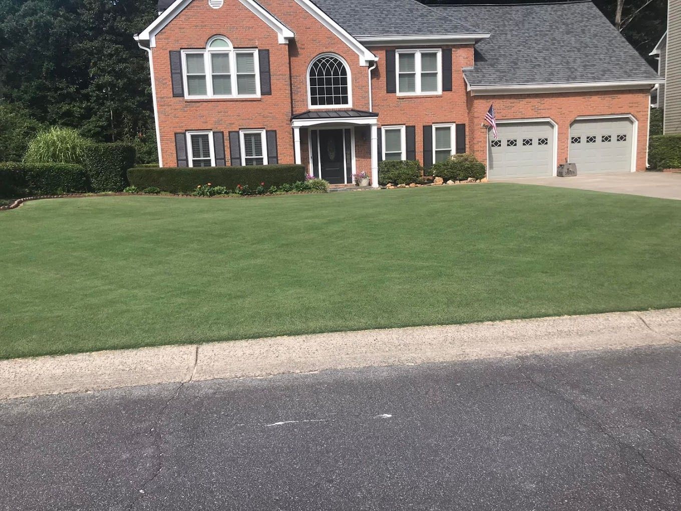 A large brick house with a lush green lawn in front of it