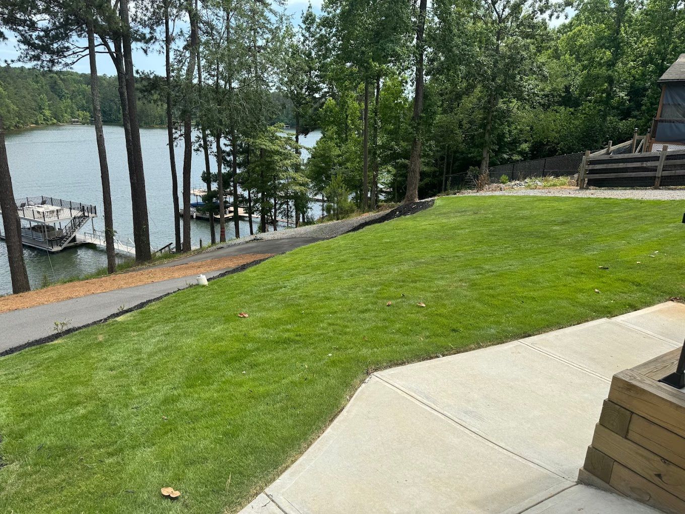 A large lawn with a view of a lake and trees.