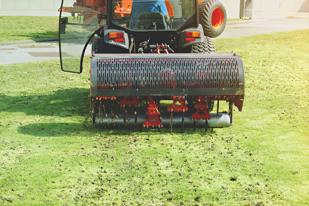 A man is driving a tractor on a lush green lawn.