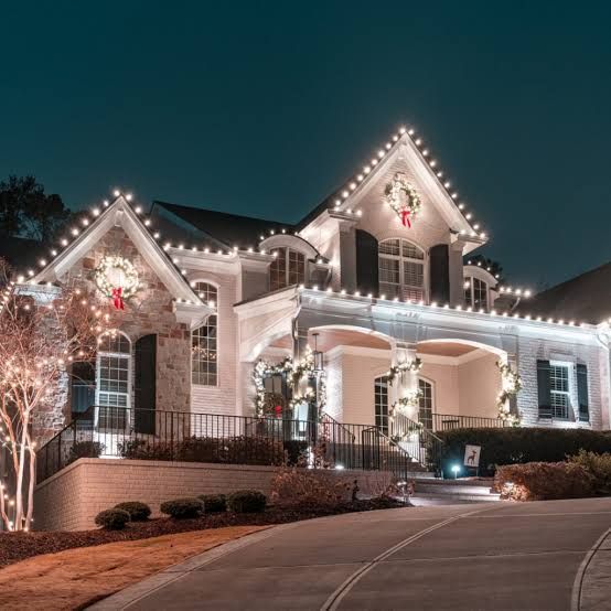 Atlanta brick house at night outlined with white holiday lights along the roof and porch, viewed from the driveway