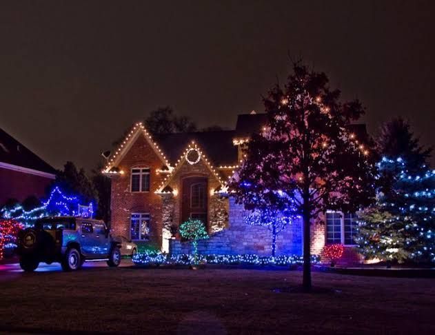 Woodstock, GA lit with colorful holiday lights at night, with a tree and parked truck in the yard