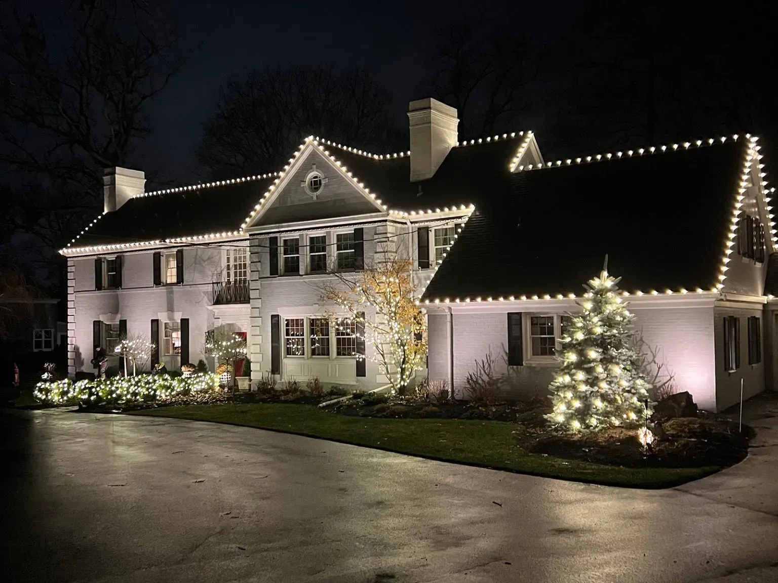 Woodstock, ga house outlined with white Christmas lights and decorated trees at night
