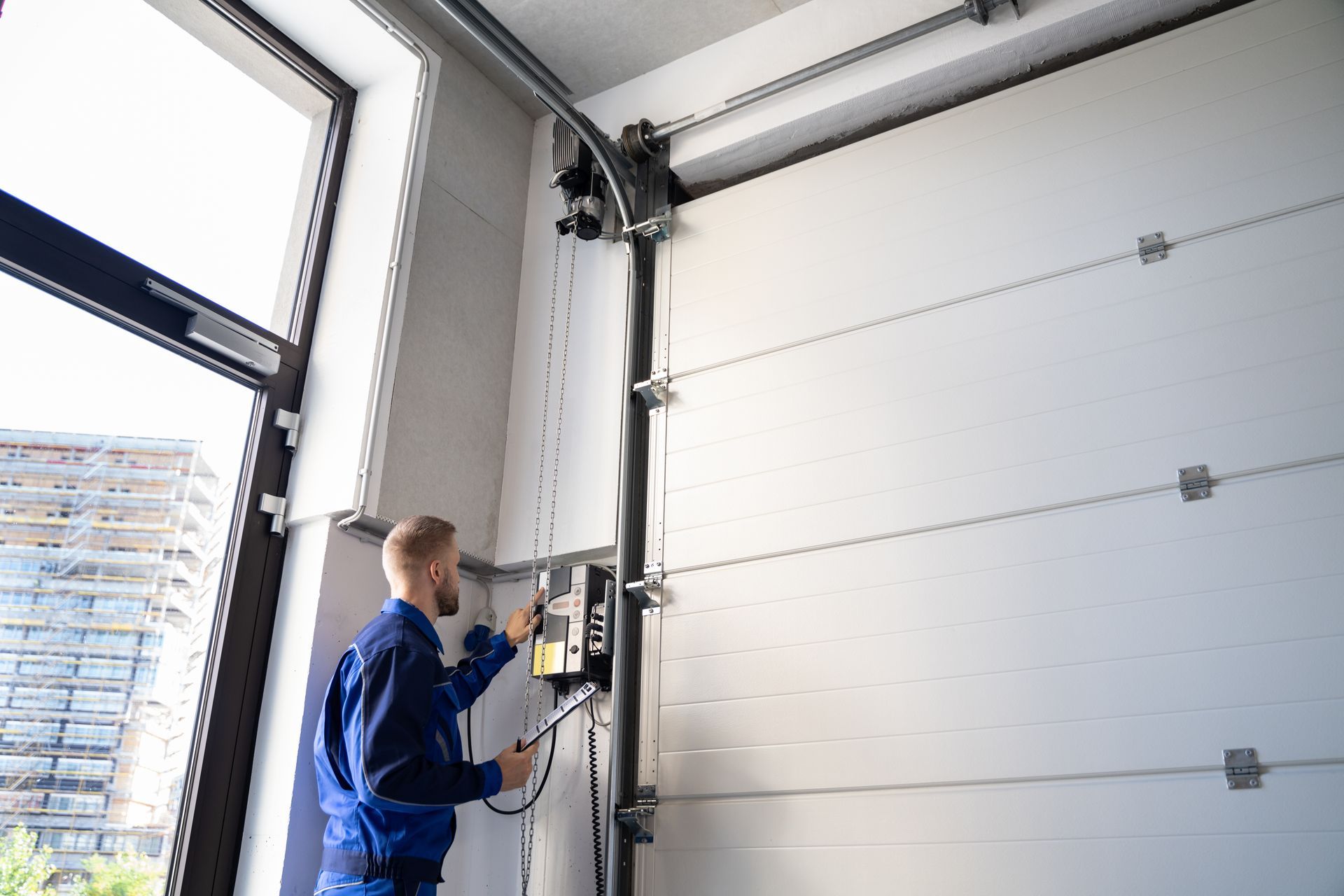 Technician operating control panel to adjust a large industrial garage door.