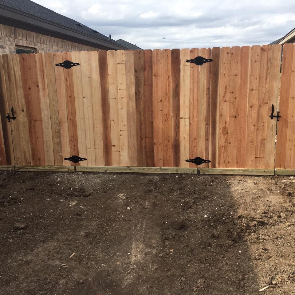 Wooden fence with decorative black hardware in a yard.
