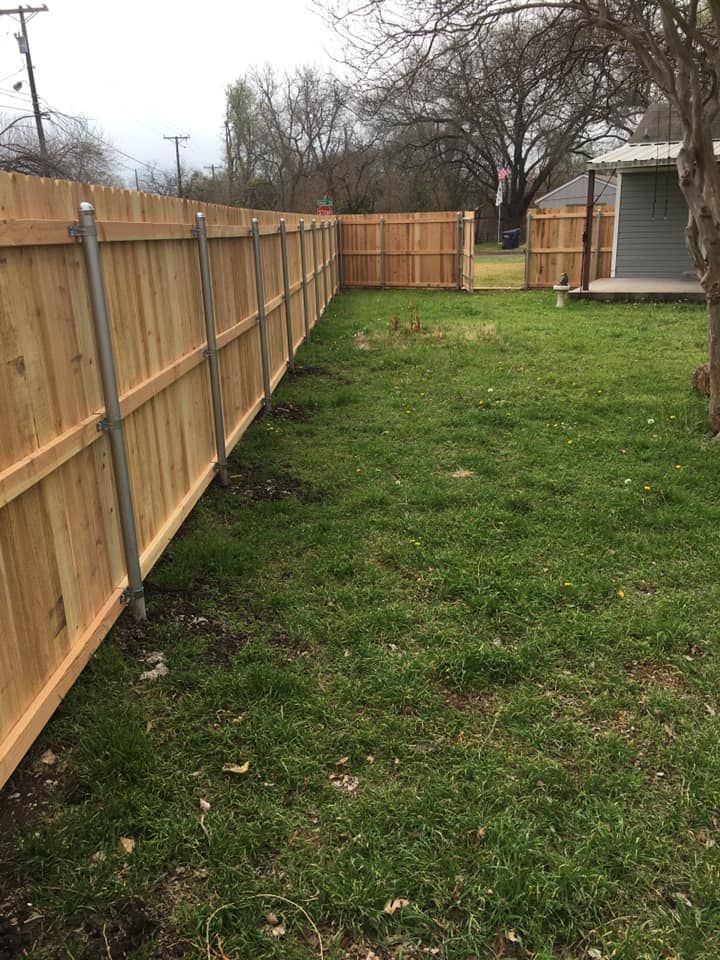 Wooden fence enclosing a grassy backyard.