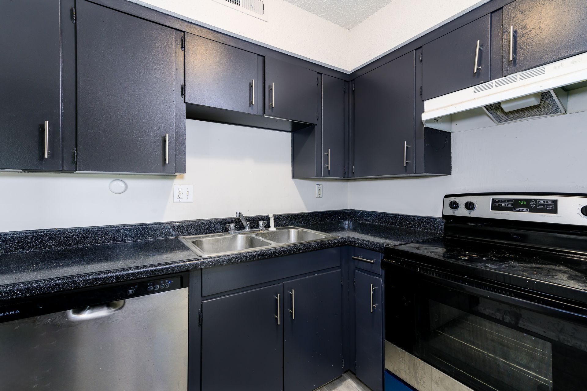 A kitchen with black cabinets and stainless steel appliances